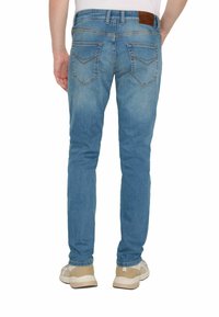 Jeans skinny blu con una finitura scolorita e cuciture a contrasto. Presentano due tasche posteriori e un'etichetta in pelle marrone sulla cintura.