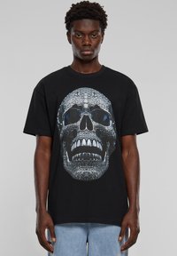 Black t-shirt featuring a large graphic of a detailed skull with textures resembling reptile scales and reflective blue accents.