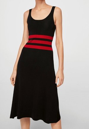 Zwarte mouwloze midi-jurk met ronde halslijn en drie horizontale rode strepen rond de taille, gedragen door een staand persoon.