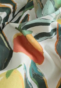 Lettert stof med et blomstermønster i gule, orange og grønne farver, som skaber et tekstureret, lagdelt udseende.