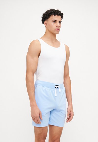 Camisola sem mangas em tecido branco com alças largas, combinada com calções azul claro. Os calções têm uma cintura elástica e cordão branco.