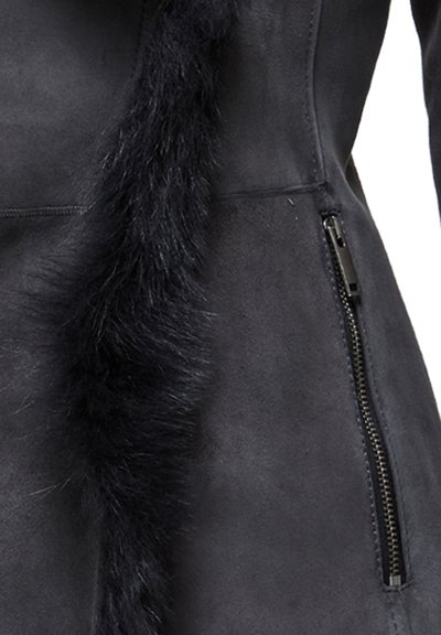 Zwarte suede jas met een zijrits en een lange, zachte bontdetail langs de voornaad. Gladde textuur met een stijlvolle uitstraling.