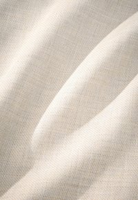 Lys beige, struktureret stof med et vævet mønster, der har subtile variationer i nuancer og en blød, glat overflade.