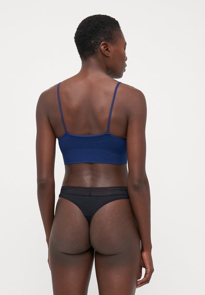 Tamnoplava bralette s tankim naramenicama; crni tanga s suptilnim logotipom; mekana, glatka tkanina; uski dizajn.
