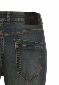 Dark blue denim jeans with a smooth texture, featuring a leather patch at the waistband and back pockets with contrasting stitching.
