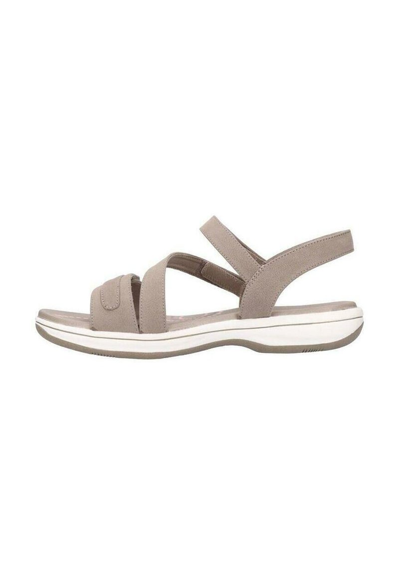 Sandalias beige con correas cruzadas, cierre de velcro y una suela blanca acolchada con una suela exterior texturada en gris.