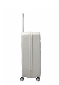 Maleta rígida blanca con mango telescópico extendido y cuatro ruedas giratorias blancas y negras, de pie sobre un fondo blanco.