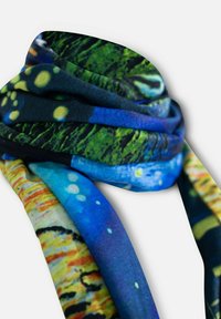 Étole en soie colorée présentant un mélange de motifs bleus, verts et dorés, avec une texture douce et un design fluide, drapée de manière élégante.