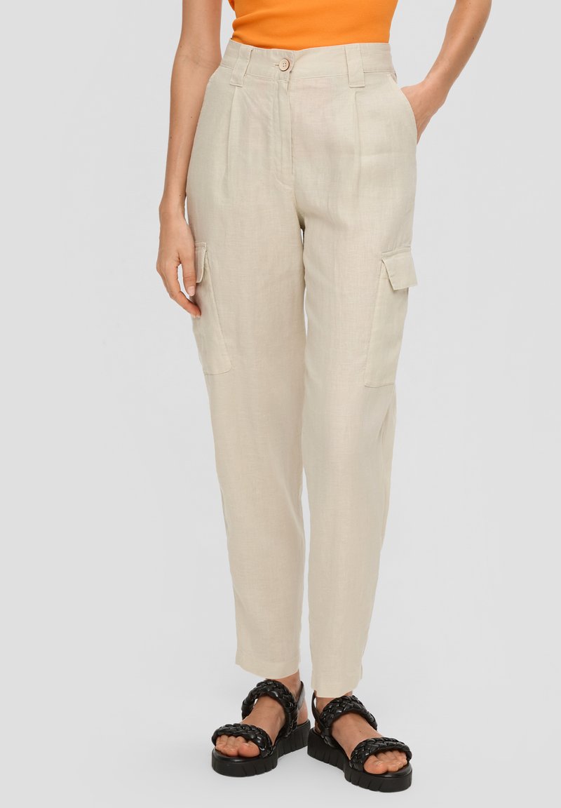 Beige linnen cargobroek met zijzakken, getailleerde pasvorm, hoge taille en opgerolde zoom. G gedragen met zwarte gevlochten sandalen.