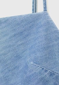 Light blue denim fabric with a smooth texture, featuring a triangular pocket and adjustable straps. Simple design with a clean finish.