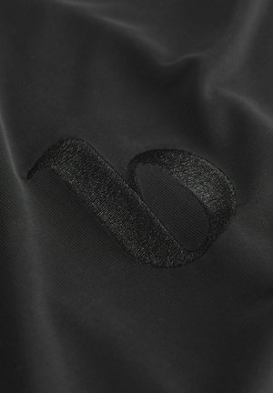 Schwarzer Stoff mit einem strukturierten, bestickten Logo in einem eleganten, minimalistischen Design. Die Oberfläche ist glatt mit subtiler Schattierung.