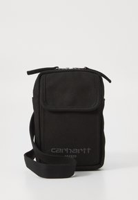 Borsa a tracolla nera in canvas con chiusura lampo, pattina frontale e tracolla regolabile. Presenta un logo impresso. Design rettangolare compatto.