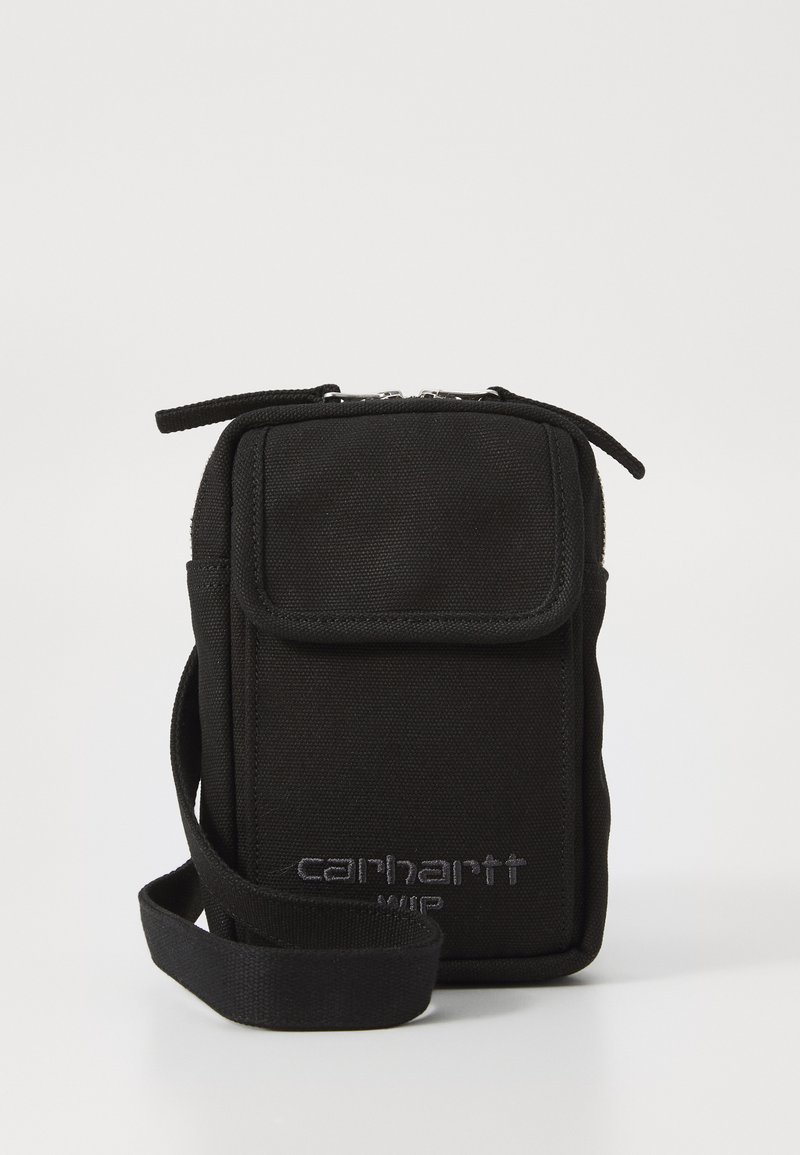Borsa a tracolla nera in canvas con chiusura lampo, pattina frontale e tracolla regolabile. Presenta un logo impresso. Design rettangolare compatto.