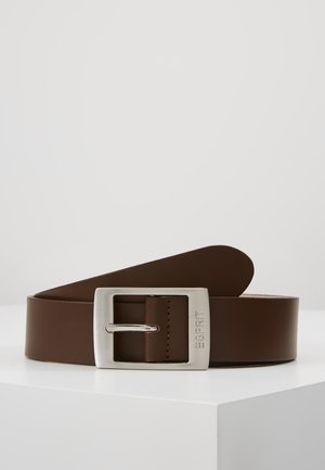 Ceinture en cuir marron avec une boucle rectangulaire en argent gravée du nom de la marque, enroulée et présentée sur une surface blanche.