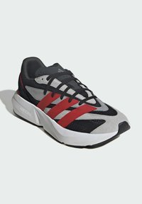 Športové tenisky so zvrškom z sieťoviny a z semišu v sivej, čiernej a červenej farbe. Obsahujú čierne šnúrky, tri červené pruhy a bielu medzipodrážku.