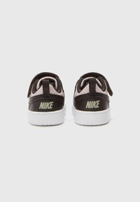 Baskets Nike noires et roses avec une semelle blanche. Les caractéristiques incluent du cuir lisse, un col rembourré et une marque visible sur le talon.