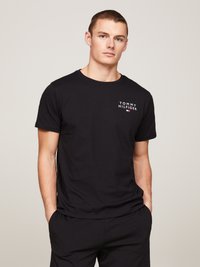 Zwarte katoenen T-shirt met een klein wit Tommy Hilfiger-logo op de borst. Ronde halslijn en korte mouwen; eenvoudig, casual ontwerp.