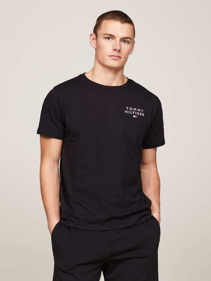 Fekete pamut póló, mellyel kicsi fehér Tommy Hilfiger logo díszíti a mellrészt. Kerek nyakkivágás és rövid ujjak; egyszerű, laza stílus.