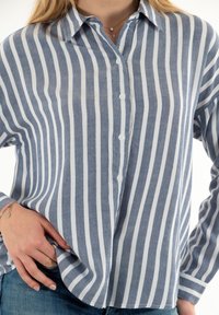 Camisa de botones a rayas azul y blanca, hecha de tejido ligero, con un cuello clásico y mangas largas de corte relajado.