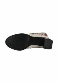 Suola di gomma nera di una scarpa con motivi floreali testurizzati. Parte superiore realizzata in tessuto leggero con motivo floreale nei colori pastello. Dettaglio del tacco a blocco.