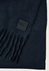 Marineblauer Schal aus weichem Stoff, mit fransigen Kanten und einem strukturierten schwarzen Etikett mit eingeprägtem Logo und Markennamen.