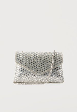 Pochette argentée avec des motifs diagonaux en strass et une bandoulière chaîne argentée sur un fond blanc uni.