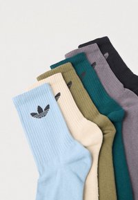 Pięć par prążkowanych skarpet w kolorach: niebieskim, beżowym, oliwkowym, morskim, szarym i czarnym, każda z czarnym logo na mankiecie.