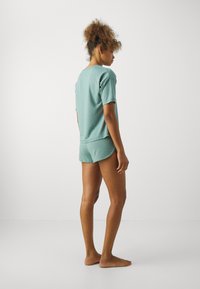 Ljus turkos loungeklädesset bestående av en kortärmad topp och shorts. Mjuk bomullsblandning med en avslappnad passform. Inga synliga mönster eller detaljer.