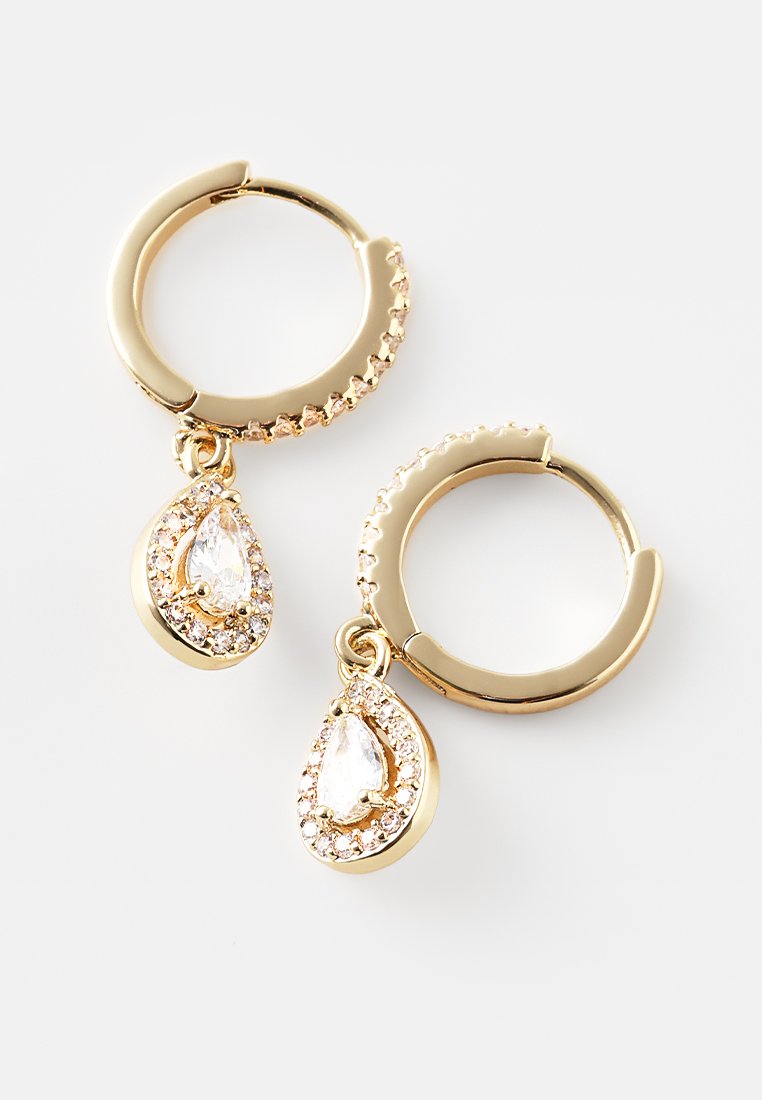 Boucles d'oreilles en or en forme de créoles, mettant en valeur un bijou clair en forme de poire entouré de petits cristaux scintillants, avec un design texturé et strié sur les créoles.