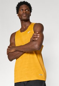 Κίτρινο αθλητικό αμάνικο μπλουζάκι με υφασμάτινη επιφάνεια, διακοσμημένο με το λογότυπο Asics σε λευκό χρώμα στο στήθος και άνετη εφαρμογή.