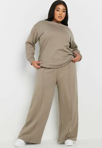 Tvådelad lounge-set i ljus taupe. Långärmad crewneck sweatshirt och vida byxor med sidosömmar. Mjukt, bekvämt tyg.