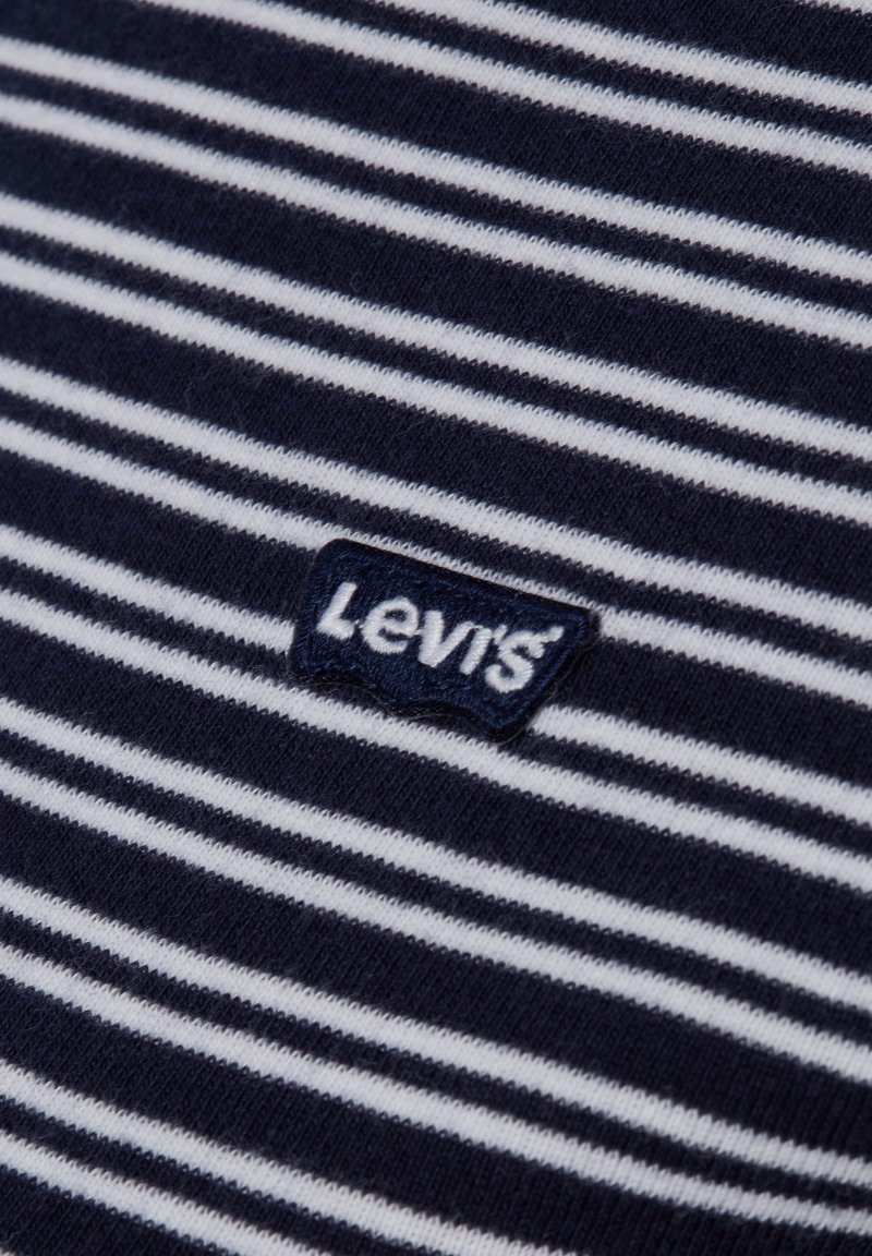 Marineblauw en wit stof met horizontale strepen en een gestikte Levi's logo patch in marineblauw en wit garen.