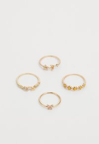Conjunto de cuatro anillos de oro: uno con acentos florales, otro con piedras transparentes, uno con piedras amarillas y un cuarto con un detalle de piedra rosa.