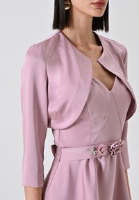 Abito di raso rosa con maniche a tre quarti, scollo a V e dettagli floreali in vita. Presenta un colletto strutturato e una texture liscia.