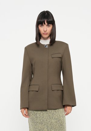 Brown tailored blazer with long sleeves, two front pockets, and a decorative button, paired with a textured gray-green skirt.