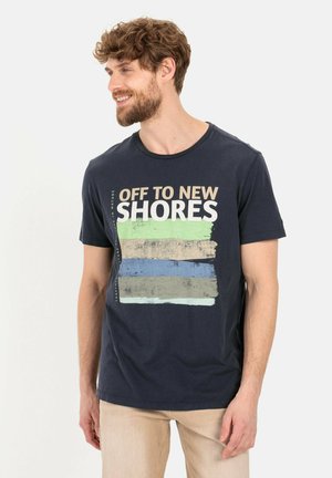 Marineblauwe katoenen t-shirt met de tekst "OFF TO NEW SHORES" en horizontale penselenpatronen in groen, blauw en beige. Korte mouwen.