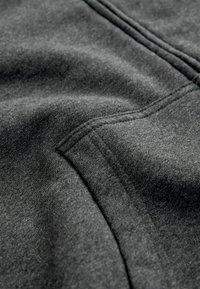 Grauer Stoff mit einer glatten Textur, der subtile Nähdetails und ein leicht gebürstetes Finish aufweist. Weiches und leichtes Material.