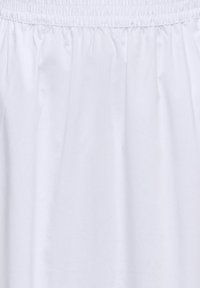 Jupe blanche avec ceinture élastique froncée et texture de tissu lisse, montrée en gros plan.