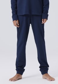 T-shirt à manches longues en coton bleu marine associé à un pantalon ample assorti. Le tissu est lisse avec une texture douce et des poignets élastiques aux chevilles.