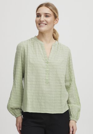 Light green, textured blouse with a round neckline, button placket, and gathered long sleeves; relaxed fit with a flowy shape.