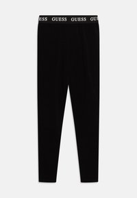 Svarta leggings i en slät tygkvalitet, med en vit "GUESS"-logotyp på den elastiska midjebandet. Fitted design med en avsmalnande ben.