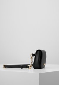 Sort lædertaske med tværstrop i rektangulær form, gyldne metaldele og aftagelig kæderem. Detaljeret tekstureret overflade.