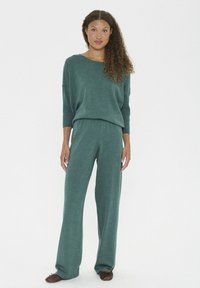 Grünes Strick-Loungewear-Set mit weit geschnittenen Hosen und einem lässig geschnittenen Oberteil. Mit einem Bootsausschnitt und gerippten Ärmeldetails.