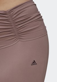 Paarse hoge sportleggings met een geplooid ontwerp en een gladde textuur. Voorzien van het zwarte Adidas-logo op het onderbeen.