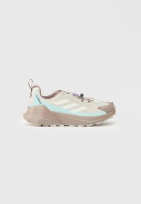 Lichte trailrunningschoenen met een beige en mint bovenkant, gestructureerd meshontwerp, reflecterende details en een bruine rubberen zool.