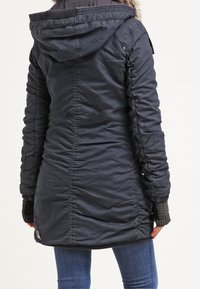 Marinblå puffjacka med huva och konstpäls, med en texturerad yta, ribbade ärmslut och en åtdragen midja för en figursydd look.