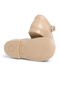 Pantofle din piele bej cu toc rotunjit, curea ajustabilă și talpă din cauciuc texturat, având un model în carouri și logo-ul brandului.
