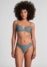 Ensemble soutien-gorge et culotte en teal atténué. Le soutien-gorge a des coques moulées avec des bretelles réglables et un bouton décoratif. La culotte présente une texture rayée subtile.