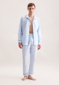 Ensemble de pyjama bleu clair composé d'une chemise à boutons avec col et passepoil noir contrastant, associée à un pantalon avec taille élastique assorti.