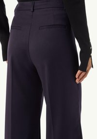 Wide-leg trousers in dark purple fabric featuring a smooth texture, back pockets, and a tailored fit with a high waist.